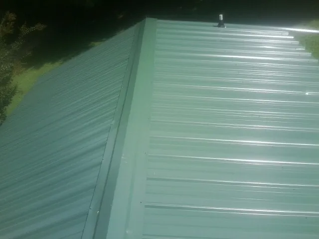 New green metal panels meeting at the ridge of a roof — Flat Roof Repair work by our crew in Silver Gate