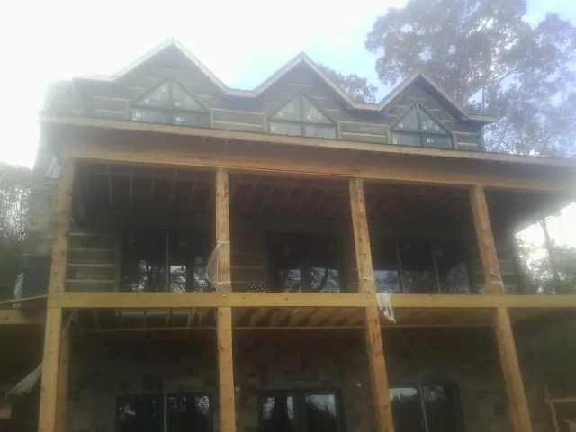 Dormers and porch framing on a large log home under construction — Roof Coating work by our crew in Silver Gate