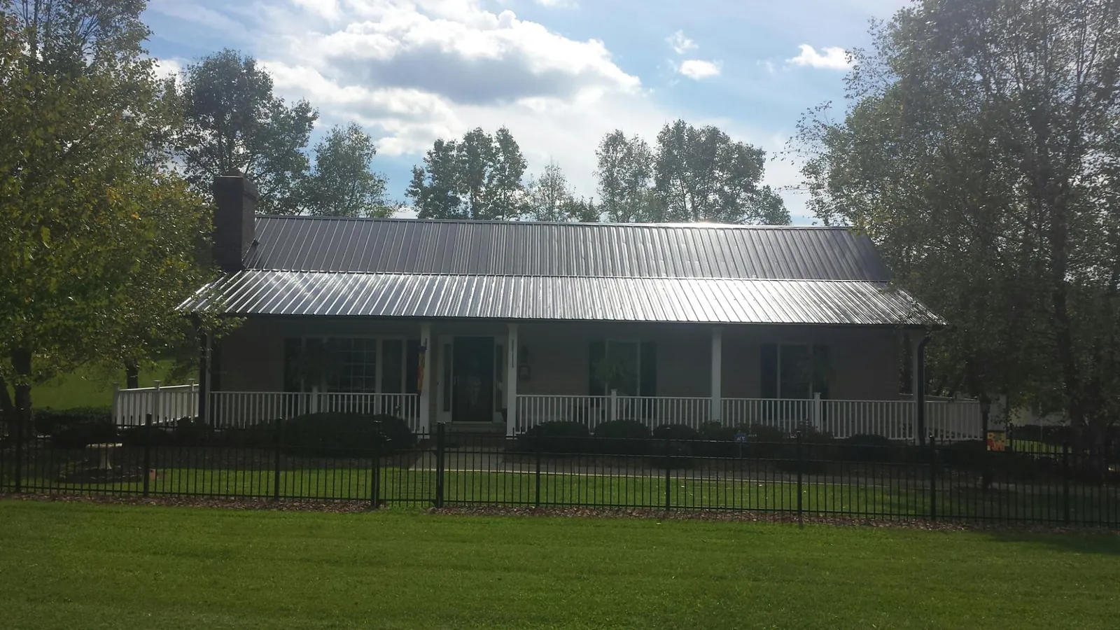 Gray metal roof on a brick ranch with a full width front porch — Gutter Guard Installation work by our crew in Silver Gate