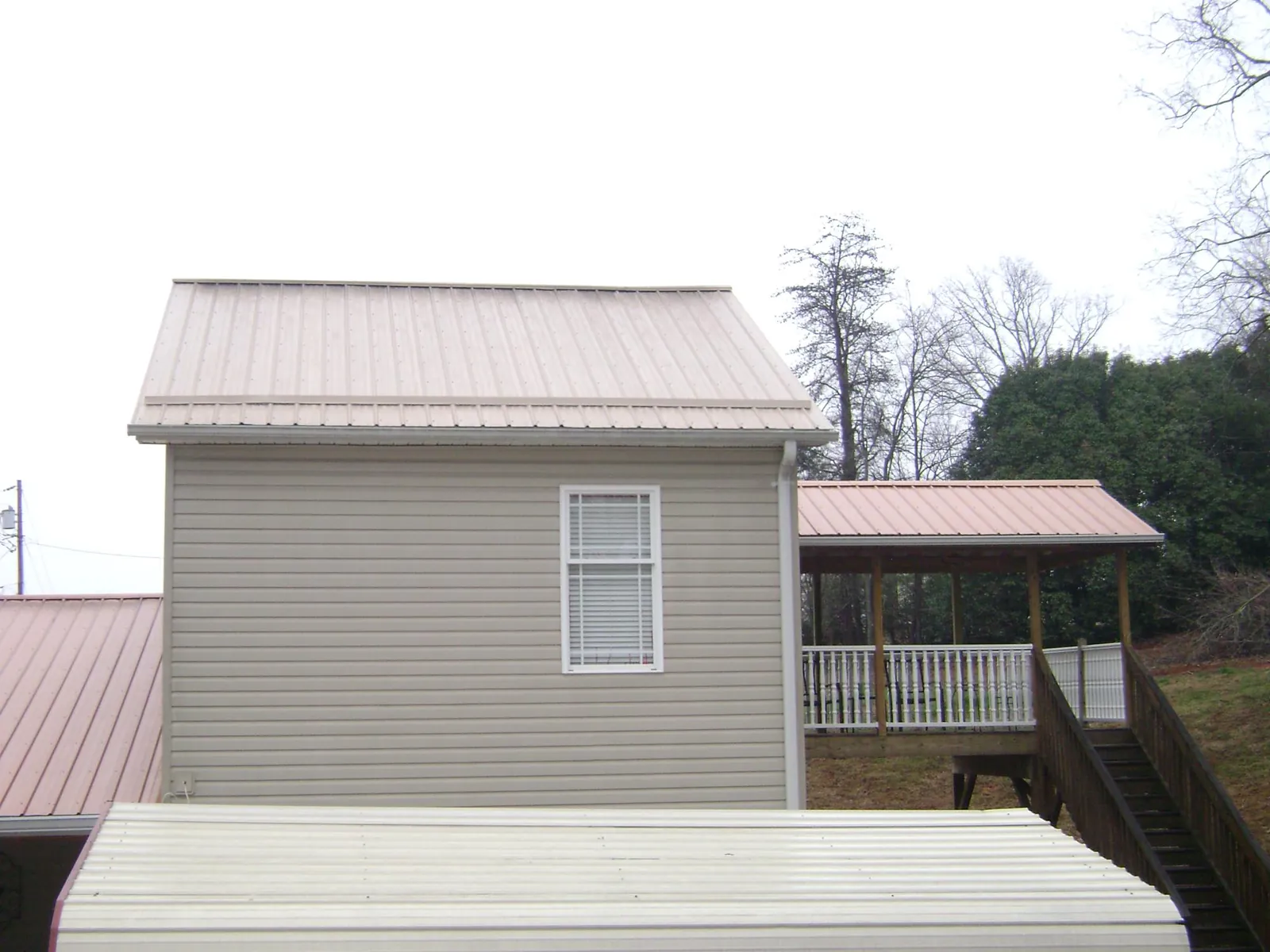 Tan metal roofs on a two story addition and attached porch, from a Roof Replacement job in Silver Gate